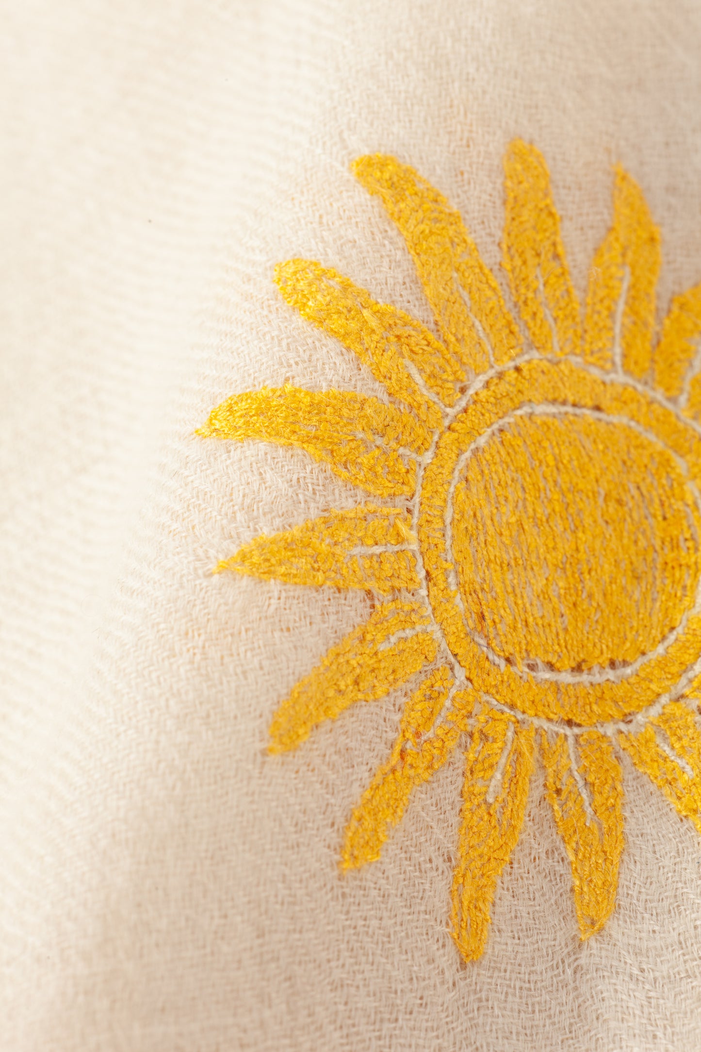 Nahaufnahme goldgelbe Sonnenstickerei auf naturweißem Kaschmir – The Adorned Carré Sun Cares von Mārīci