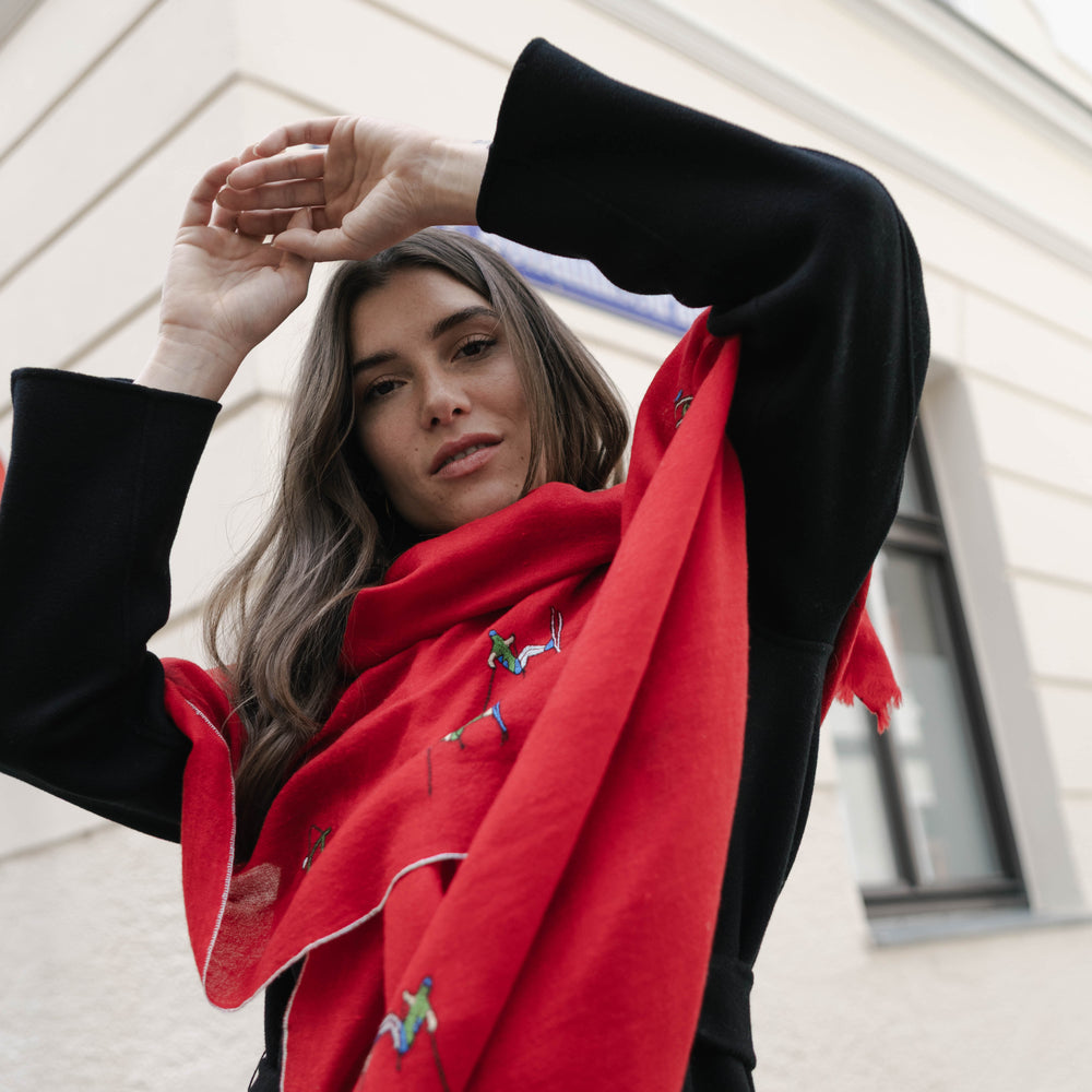 
                      
                        Model trägt den roten Pashmina Schal „The Adorned – Alpine Life“; handgefertigt aus Kaschmir mit alpinen Stickmotiven, Ausdruck von Eleganz und Wärme.
                      
                    