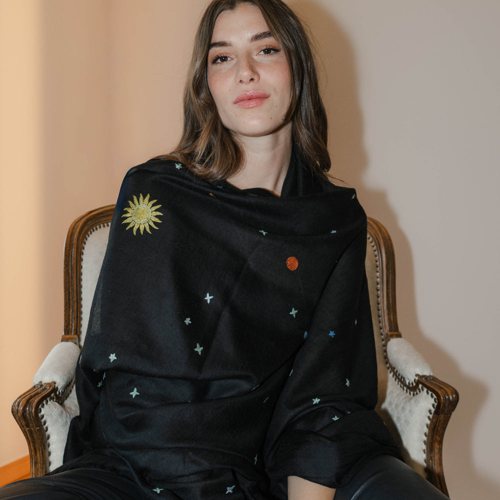 
                      
                        Model trägt den schwarzen Pashmina Schal „The Adorned – Dancing Universe“ mit farbiger Universumsstickerei; handgefertigtes Kaschmir, inspiriert vom mystischen Kosmos.
                      
                    