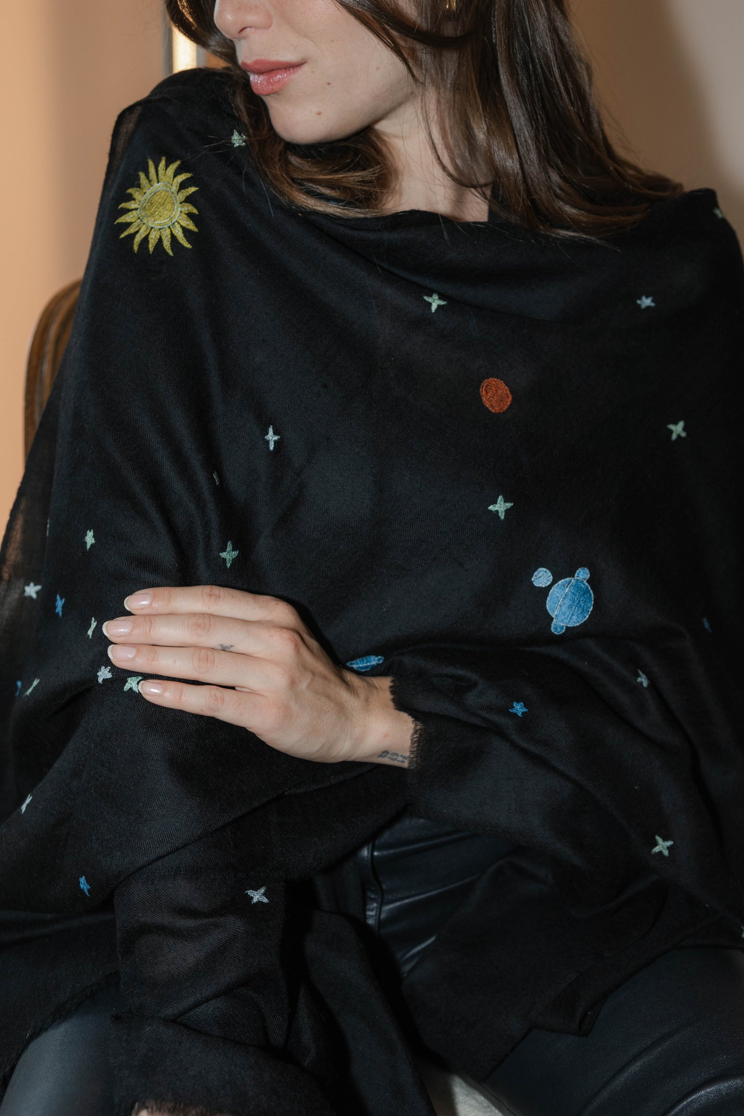 Model trägt den schwarzen Pashmina Schal „The Adorned – Dancing Universe“ mit farbiger Universumsstickerei; handgefertigtes Kaschmir, inspiriert vom mystischen Kosmos.