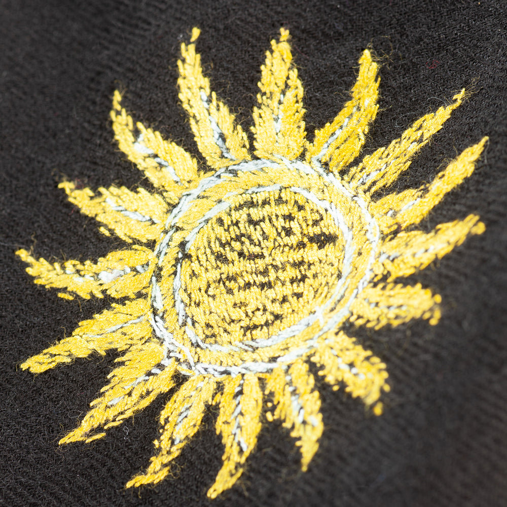 
                      
                        Detailaufnahme der Stickerei gelben Sonne Galaxiemotive des Pashmina Schals „The Adorned – Dancing Universe“; filigrane Handarbeit aus Kaschmir.
                      
                    