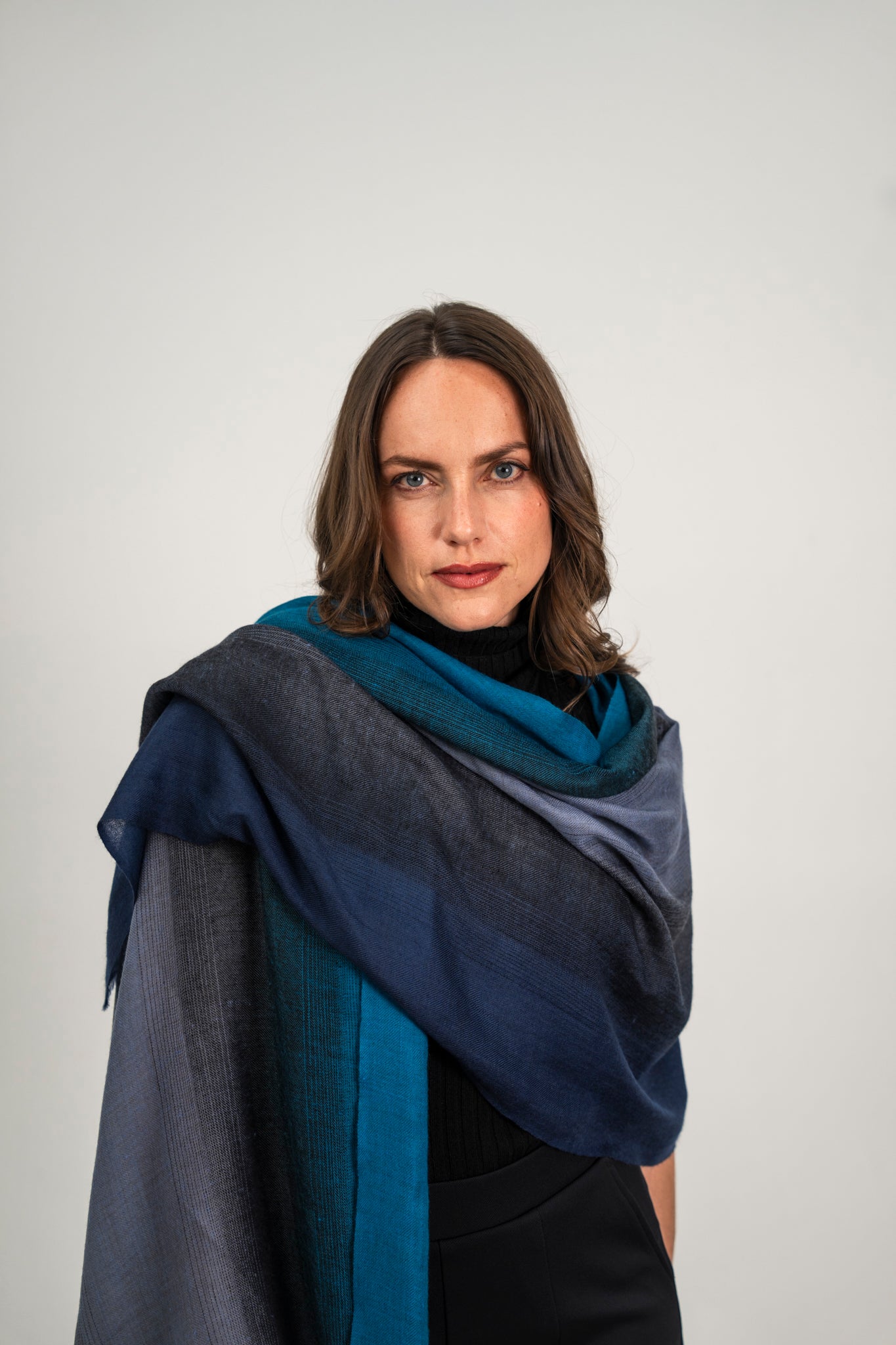 Model trägt den Kaschmir Pashmina Schal „The Breeze – Ombré Twilight“ mit elegantem Blau-Ombré-Verlauf; leicht, fließend und modern.